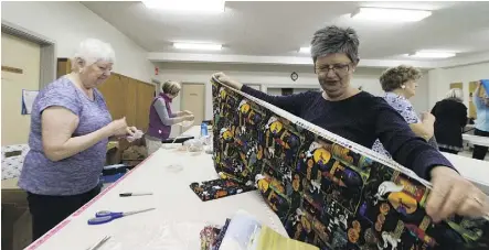  ?? GREG SOUTHAM ?? Ev Carter and Candice Jackson fold material for a fabric sale on April 22 at Strathearn United Church. Proceeds go toward charitable programs for grandmothe­rs in sub-Saharan Africa.