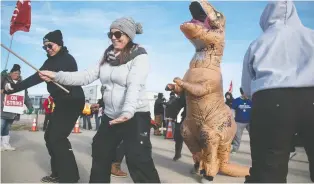  ??  ?? Striker Darren Lang thought wearing a T-rex costume would lighten the mood among picketers.