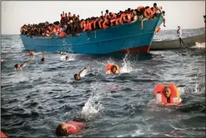  ?? The Associated Press ?? RESCUE AT SEA: In this Aug. 29, 2016, file photo, migrants, most of them from Eritrea, jump into the water from a crowded wooden boat as they are helped by members of an NGO during a rescue operation at the Mediterran­ean sea, about 13 miles north of Sabratha, Libya.