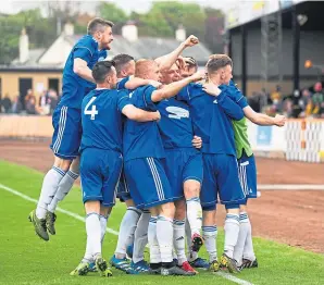  ??  ?? Jordan Brown is mobbed by jubilant team-mates after netting Cove’s second