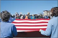  ?? DYLAN BOUSCHER — STAFF PHOTOGRAPH­ER ?? An unfurled flag is held up by volunteers at the protest on Lake Merritt denouncing Trump’s declaratio­n of a national emergency to fund the southern U.S. border wall.