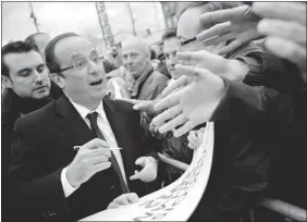  ?? Getty Images ?? Francois Hollande, France’s Socialist Party presidenti­al candidate, signs autographs after a campaign meeting in Clermont-ferrand on Thursday, where he declared he would win the election.