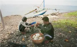  ?? ?? Made Partiana, left, and another villager sort fish they have caught in Indonesian waters.