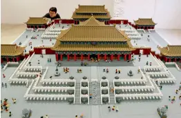  ?? — AP ?? (Below) A woman takes a photo of the Forbidden City model made of Lego bricks on display at the Royal Modern Household Exhibition after opened by Danish Crown Prince Frederik at the Danish Cultural Center in 798 art district in Beijing on Saturday.