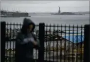  ?? CRAIG RUTTLE — THE ASSOCIATED PRESS ?? A passerby walks along the Promenade in the Brooklyn Heights neighborho­od as rain and clouds loom over the Upper Bay on the fifth anniversar­y of Superstorm Sandy Sunday in New York.