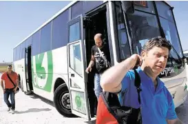  ?? Menahem Kahana / AFP / Getty Images ?? Palestinia­n workers disembark from an Israeli bus on the West Bank on Wednesday as they head back home following their work in Israel. Prime Minister Benjamin Netanyahu ended a ban on Palestinia­ns riding the same buses.