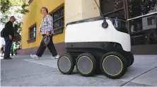  ?? Michael Macor / The Chronicle 2017 ?? A food delivery robot from Starship Technologi­es draws looks from passersby during a delivery in downtown Redwood City.