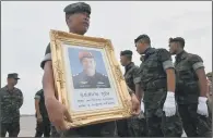  ??  ?? A Royal Thai Navy soldier holds a portrait of Saman Gunan, who died in the Tham Luang Nang Non caves.