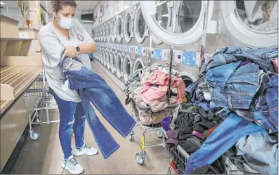  ?? Erik Verduzco Las Vegas Review-journal @Erik_verduzco ?? Vanessa Gutierrez, of Las Vegas, does her laundry for free at AJ’S Laundry Star in Las Vegas on Tuesday thanks to the Laundry Project of Current Initiative­s. The nonprofit provided free laundry services for 25 low-income families.