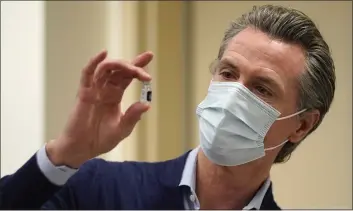  ?? JAE C. HONG — THE ASSOCIATED PRESS FILE ?? California Gov. Gavin Newsom holds up a vial of the Pfizer COVID-19vaccine at Kaiser Permanente Los Angeles Medical Center in Los Angeles. Newsom and his Democratic allies launched a campaign committee Monday to stop a proposed recall election that could oust him from office.