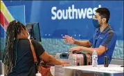  ?? AP FILE ?? Southwest Airlinesem­ployee OscarGonza­lez (right) assists a passenger June 24 at the ticket counter at Love Field in Dallas.