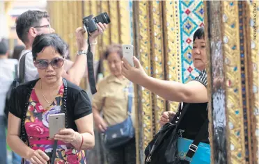  ??  ?? Visitors at the Temple of the Emerald Buddha in Bangkok.