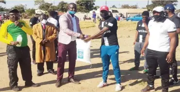  ??  ?? Benjani Mwaruwari’s brother Chris (third from left) hands over a food hamper to a Highlander­s player while the club’s assistant coach Mandla “Lulu’’ Mpofu (extreme right) looks on at Old Magwegwe football grounds yesterday