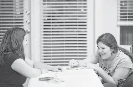  ?? Marie D. De Jesús photos / Houston Chronicle ?? Alexia Stamatis, 13, plays a board game with her mother, Karen Aramburu, after dinner last week at their home in Katy. The board game requires counting, which reinforces skills Alexia learns in her special education math class at West Memorial Junior...