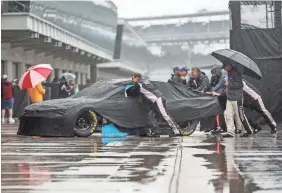  ?? JENNA WATSON/THE INDIANAPOL­IS STAR ?? Monster Energy NASCAR Cup Series crews move cars off pit road after the Brickyard 400 was postponed until Monday.