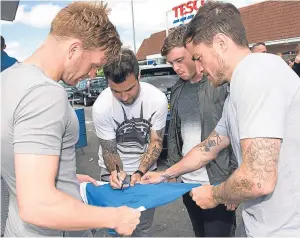  ?? Pictures: SNS. ?? Top: Tommy Wright and shirt sponsor Alan Storrar are joined by players at a shirt launch event in Perth yesterday, with players signing the new strips for supporters.