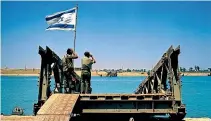  ?? AP ?? In this June 1967 file photo, Israeli soldiers stand at a destroyed bridge looking over the Egyptian bank of the Suez Canal.