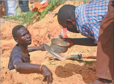  ?? BOUREIMA HAMA / AGENCE FRANCE-PRESSE ?? A man examines a bowl near a digger searching for gold in Kafa-Koira, south of Niger capital Niamey. Arriving on motorcycle­s and donkeys, in cars, or even on foot, hundreds have flocked to a site in the south of the country hoping to strike gold.