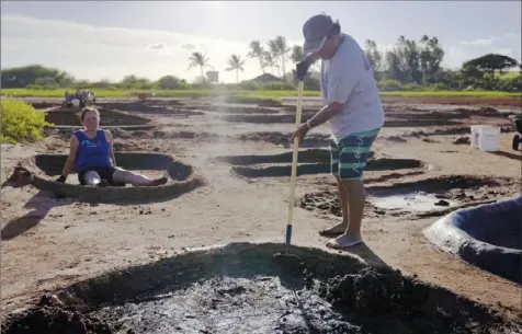  ?? Jessie Wardarski/Associated Press ?? Roz Choi, left, and friend Eddie Topenio tend to Choi family salt beds in July in Hanapepe, Hawaii. Over generation­s, Choi family members have dedicated themselves to the cultural and spiritual practice of “paakai,” or Hawaiian salt.