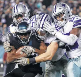  ?? Matt Rourke / Associated Press ?? Cowboys middle linebacker Jaylon Smith, top left, linebacker Leighton Vander Esch, center, and free safety Xavier Woods stop Eagles receiver Nelson Agholor.