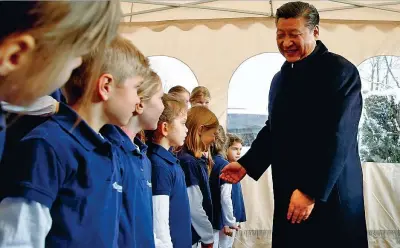  ??  ?? Il presidente cinese Xi Jinping si compliment­a con i bambini del coro che si sono esibiti nella stazione ferroviari­a di Kehrsatz in Svizzera