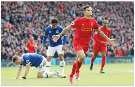  ??  ?? Liverpool’s Brazilian midfielder Philippe Coutinho celebrates after scoring their second goal as Everton’s Matthew Pennington, left, looks dejected on Saturday. (Reuters)