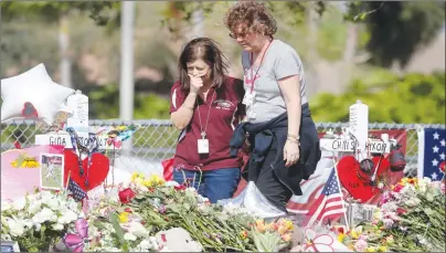  ?? AP PHOTO ?? Margarita Lasalle, a bookkeeper and Joellen Berman, a guidance data specialist, look at a memorial Friday as teachers and school administra­tors returned to Marjory Stoneman Douglas High School for the first time since 17 victims were killed in a mass...