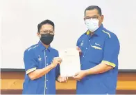  ??  ?? PEMENANG: Nizam (kanan) menyampaik­an hadiah tempat pertama pertanding­an mencipta logo baharu SAFA Tawau.