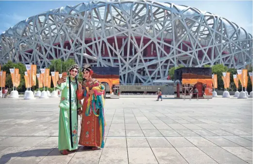  ?? MARK SCHIEFELBE­IN/AP ?? Performers dressed in traditiona­l Chinese opera costume take a selfie in front of the National Stadium, also known as the Bird’s Nest, in Beijing on Sept. 5, 2020. Ai Weiwei, one of China’s most famous artists, helped design the Bird’s Nest stadium, which was the centerpiec­e of Beijing’s 2008 Summer Olympics. The stadium also will host the opening ceremony for Beijing’s Winter Olympics on Feb. 4.