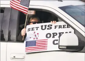  ?? Mark Lennihan / Associated Press ?? A passenger in a car participat­es in a rally of honking vehicles that passes back and forth in front of the governor’s mansion during the coronaviru­s pandemic on April 20 in Hartford. Her sign reads, “Set Us Free.” The rally, organized by CT Liberty Rally, is asking Gov. Ned Lamont to allow people to make their own decisions when it comes to their health.