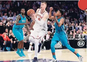  ?? AP PHOTOS ?? New York Knicks’ Kristaps Porzingis (centre) drives past Charlotte Hornets’ Malik Monk (right) to score during the second half of an NBA basketball game in New York on November 7.