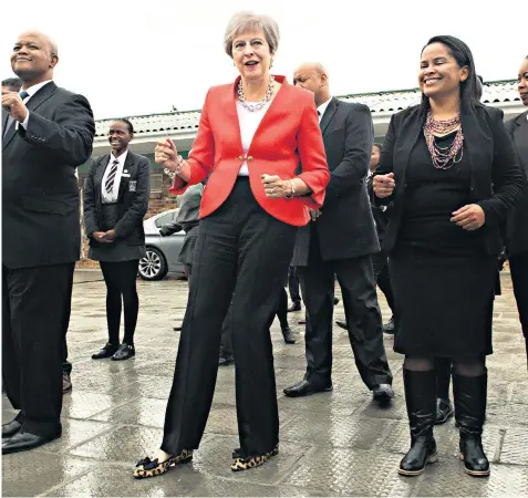  ??  ?? Dance your cares away: Theresa May joined in when students and staff at I.D. Mkize Secondary School in Cape Town performed a traditiona­l dance for the Prime Minister’s visit