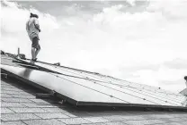  ?? David A. Funchess ?? A worker installs solar panels on a home in 2017. Solar is part of Texas’ energy present and future, but a proposal from the Pedernales Electric Cooperativ­e would make solar power more expensive.