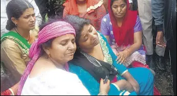  ?? BIRBAL SHARMA/HT ?? Mohli Devi (in blue) being condoled by relatives and locals after she lost her three children and sisterinla­w in the landslide near Mandi on Sunday.