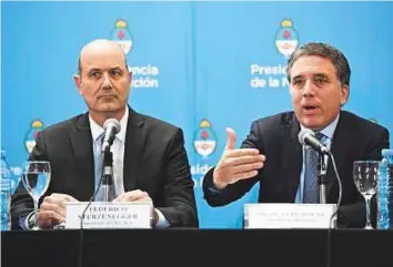  ?? AFP ?? Argentina’s Central Bank Governor Federico Sturzenegg­er (left) listens while Finance Minister Nicolas Dujovne speaks during a press conference in the capital Buenos Aires on Thursday.