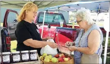  ?? Photograph submitted ?? Cathy Lynn Fletcher buys pears from Carol Roper at a recent Pea Ridge Farmers Market.