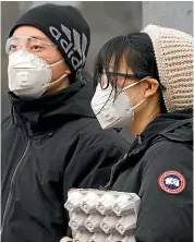  ?? AP ?? Residents wearing masks wait at a traffic light in Beijing.