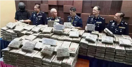  ??  ?? Job well done: Mohmad (third from left) inspecting the cannabis slabs seized during a press conference at the Kedah police headquarte­rs. With him are (starting second from left) deputy state police chief Deputy Comm Police Sahabudin Abd Manan,...