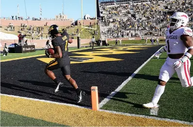  ?? AP Photo/L.G. Patterson ?? ■ Missouri running back Tyler Badie, left, scores past Arkansas defensive back Jalen Catalon during the second half of an NCAA college football game Saturday in Columbia, Mo. Missouri won the game, 50-48.