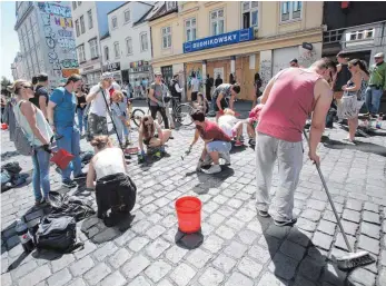  ?? FOTO: DPA ?? Großreinem­achen im Schanzenvi­ertel: Anwohner beseitigen das Chaos, das gewalttäti­ge G20-Gegner hinterlass­en haben.