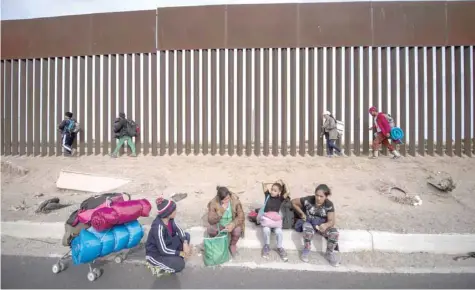  ?? — AFP ?? Central American migrants — mostly Hondurans — moving in a caravan towards the United States, walk along the metal fence on the border between Mexicali in Mexico’s Baja California State and Calexico in California on Monday.