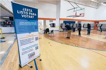  ?? DAVID ZALUBOWSKI/AP 2020 ?? A sign in Spanish is seen near voters as they cast their ballots south of downtown Denver.