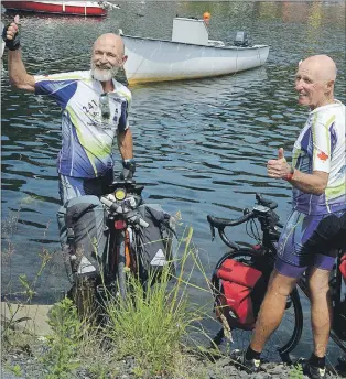  ?? JOE GIBBONS/THE TELEGRAM ?? Jim Stewart, 62, (left) and Martin Denonville, 63, dip their bicycle tires into the waters of the Atlantic Ocean on Monday afternoon in Quidi Vidi Village.