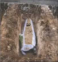  ??  ?? A coffin lies in a grave in a cemetery set up for victims of covid-19.