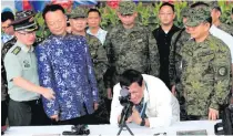  ??  ?? Duterte tries out the scope of a China-made sniper rifle, together with other automatic rifles, donated by the Chinese government during a turnover ceremony at Clark Air Base on June 28, 2017.