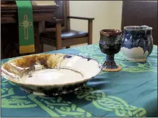  ?? Arkansas Democrat-Gazette/FRANCISCA JONES ?? The Rev. David Dyer’s Communion set rests on a table at the front of the sanctuary of Westminste­r Presbyteri­an Church in Little Rock. The set, paired with green paraments, were the two items the church had at its first service after a fire destroyed their church building on July 19, 2018.