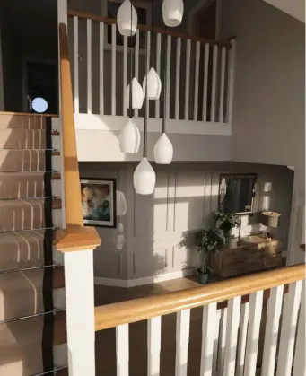  ??  ?? TOP RIGHT: A view from the stairs of the spacious, welcoming hallway, complete with light-grey wood panelling