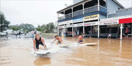  ?? PHOTOS: GETTY IMAGES ?? Board games . . . Local residents surf down the main street of Billinudge­l, in northern New South Wales, yesterday.