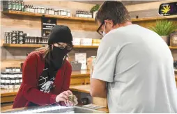  ?? The Sentinel-Record/Grace Brown ?? Suite 443 budtender Kassy Buehler shows a container of medical marijuana to a patient on Thursday.