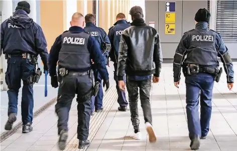  ?? FOTO: MAYNTZ ?? Bundespoli­zisten haben einen Nigerianer ohne Papiere aus einem Zug geholt und bringen ihn am Bahnhof Passau zur Identitäts­feststellu­ng.